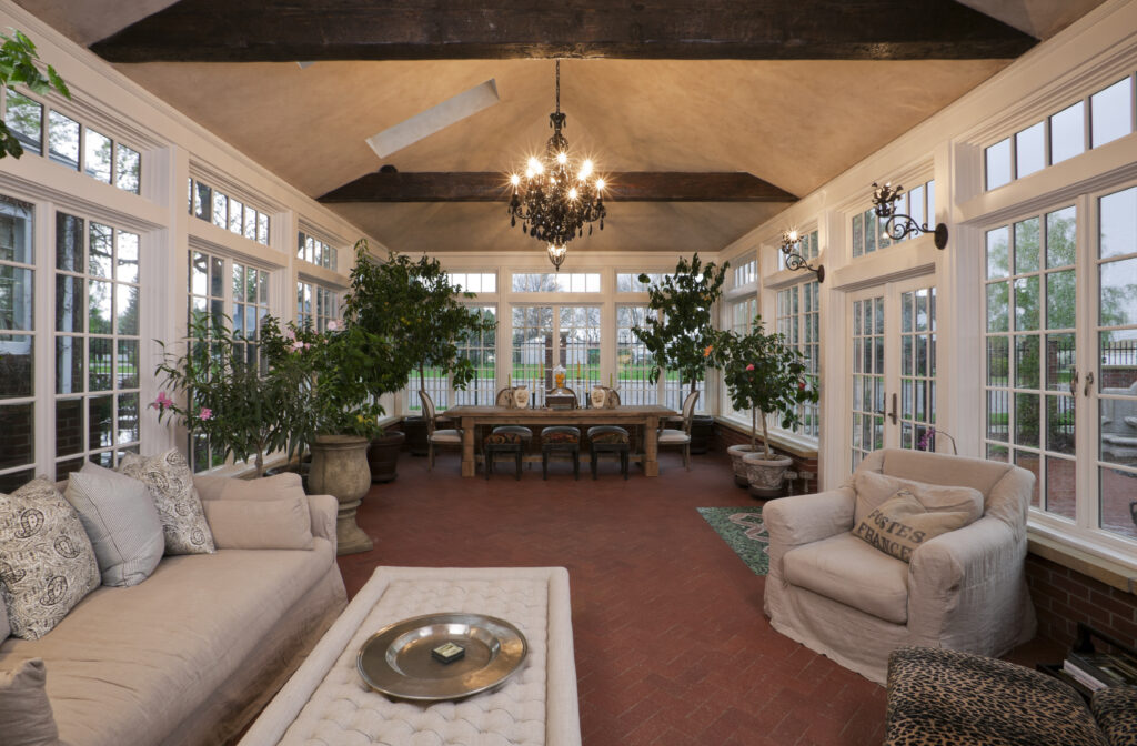 A beautifully renovated orangerie, bathed in sunlight, with elegant architectural features and lush greenery inside. The large windows allow natural light to flood the space, highlighting the intricate detailing of the structure. A harmonious blend of history and modernity, this remodel preserves the charm of the original building while offering a contemporary twist.