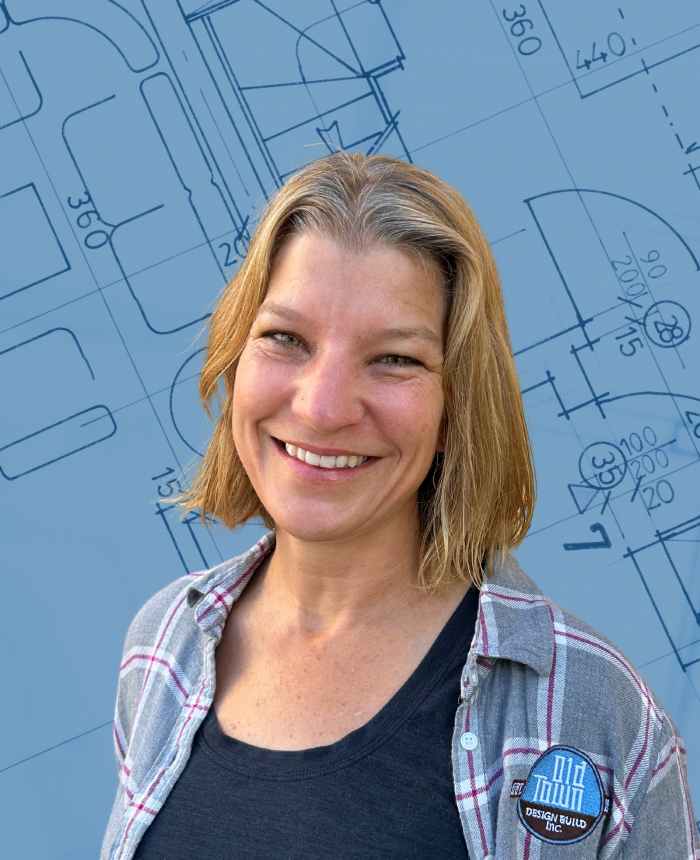 Portrait of Karen Ramsey, construction manager at Old Town Design Build in Old Town Fort Collins, Colorado. Architectural plans and a blueprint in the background.